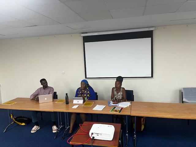 Sonia Winifred and two others sit in a panel discussion a the front of an office conference room.